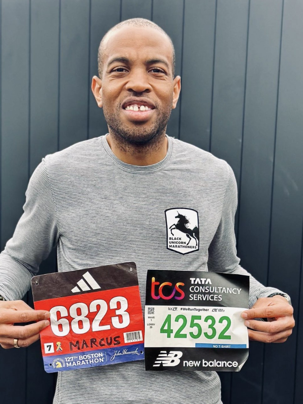 A man holding two marathon runner number tags and wearing an Oura ring.