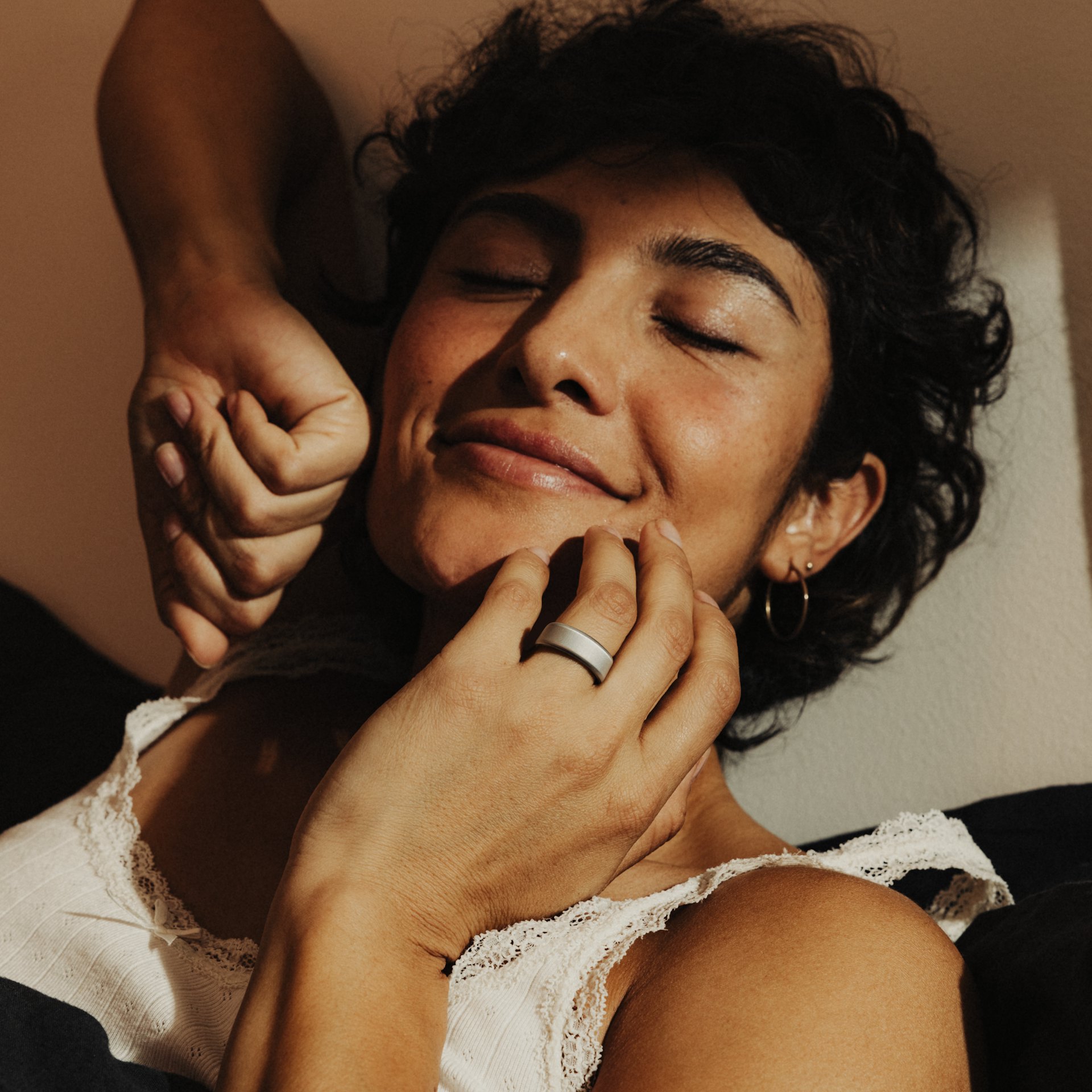 A close-up shot of a woman stretching with her hand near her face and an Oura Ring on her finger. 