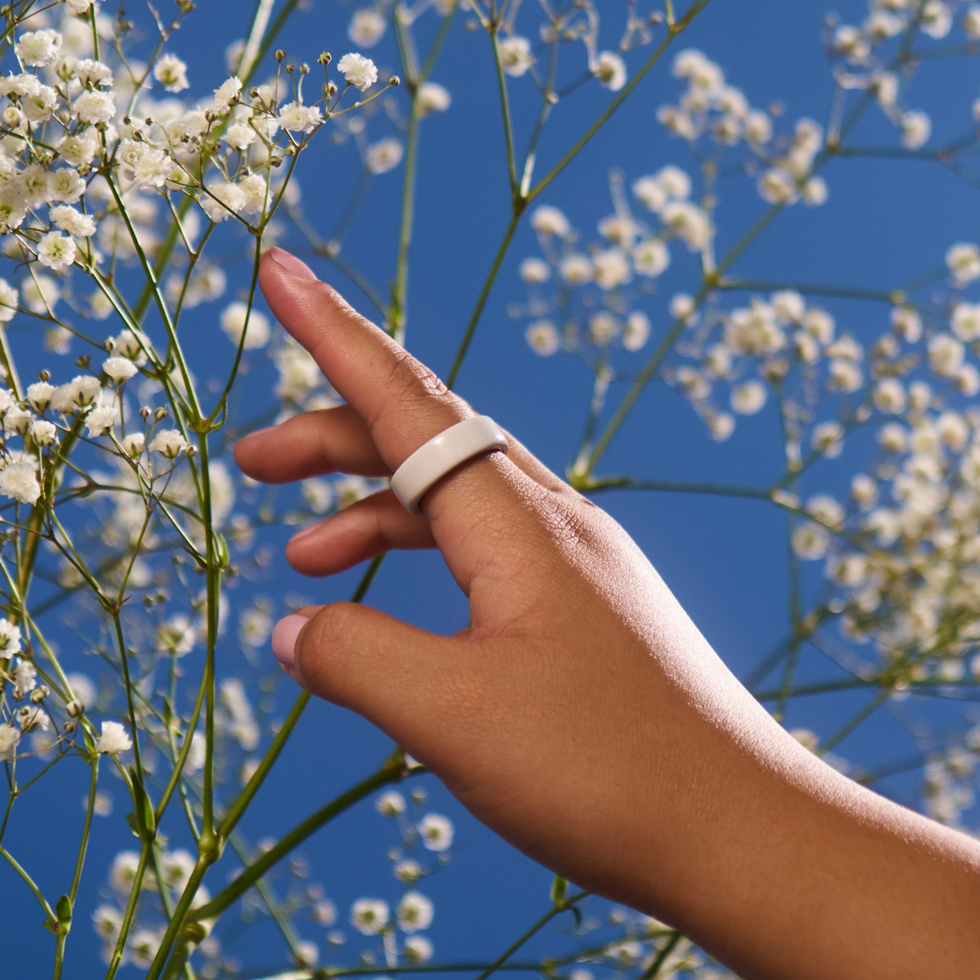 Close up of a person's hand with a Cloud Oura Ring 4 Ceramic on their finger