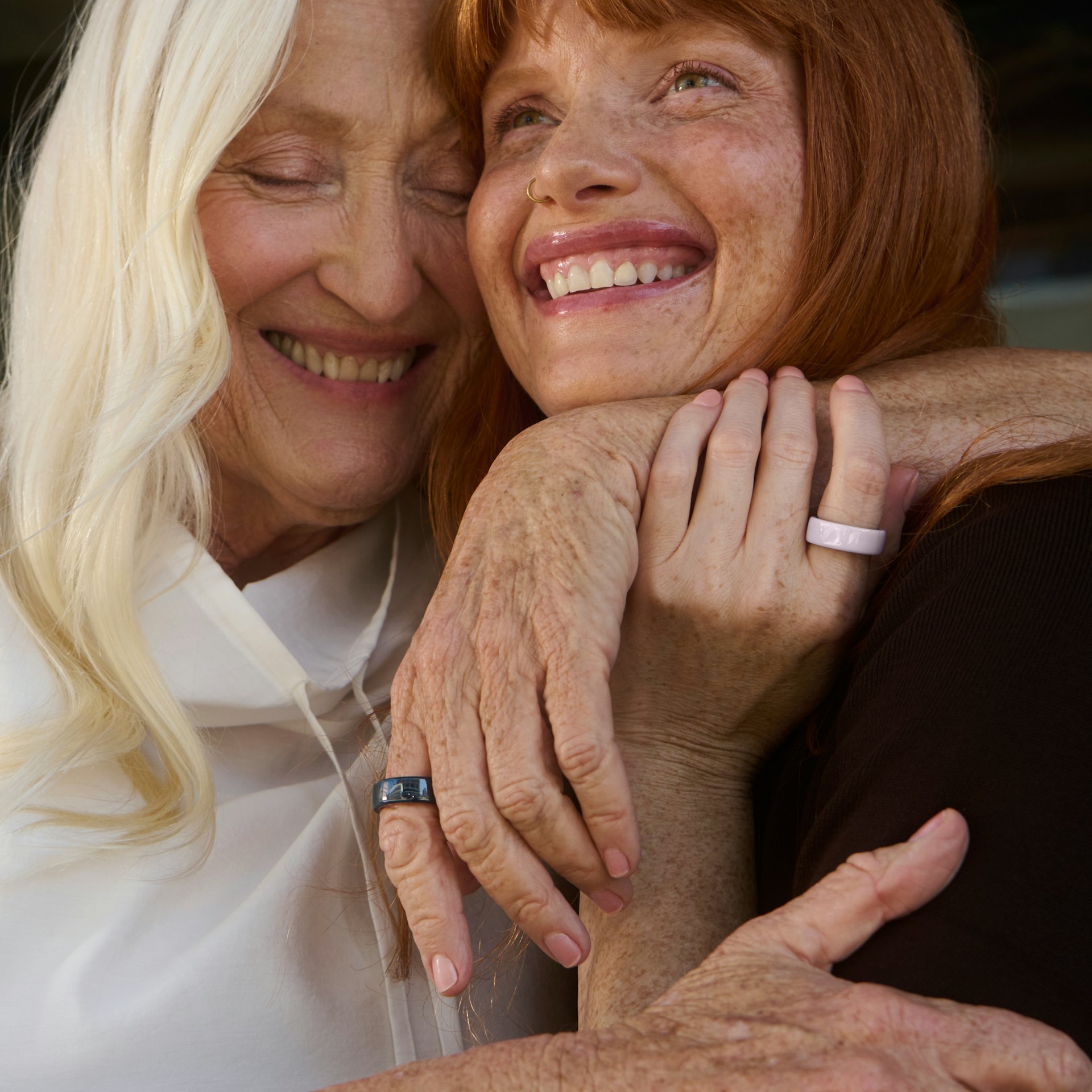 Two women wearing Oura Ring 4 Ceramic rings hug