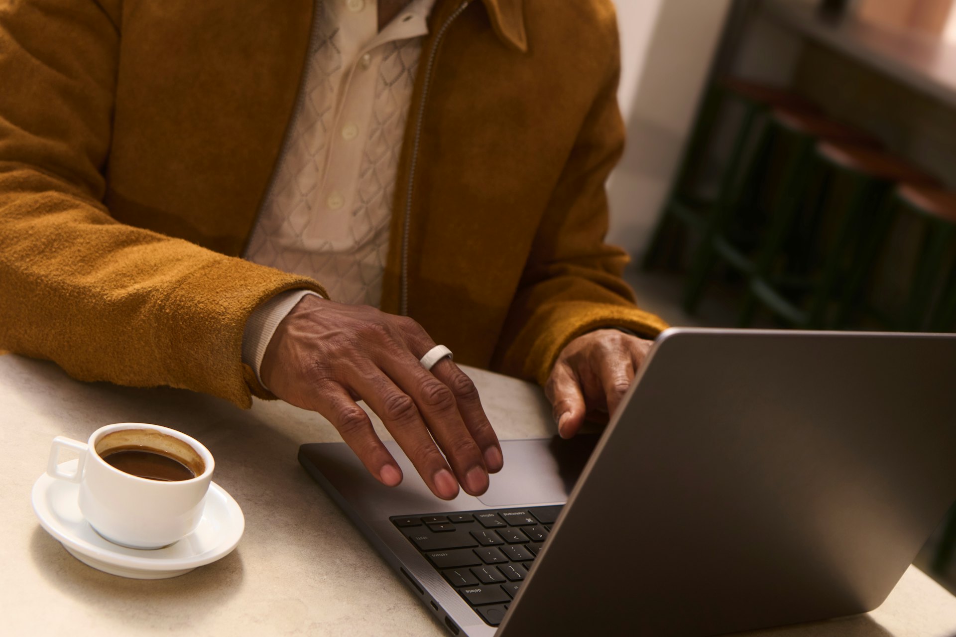 A person typing on a laptop while wearing an Oura ring