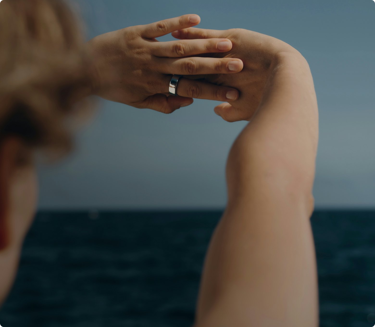 Woman wearing Oura ring stretching hands above head